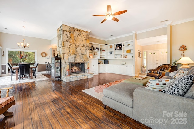 living room with hardwood / wood-style flooring, a stone fireplace, ceiling fan with notable chandelier, and crown molding