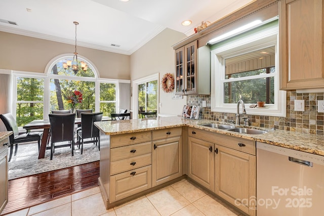 kitchen featuring pendant lighting, dishwasher, sink, kitchen peninsula, and an inviting chandelier