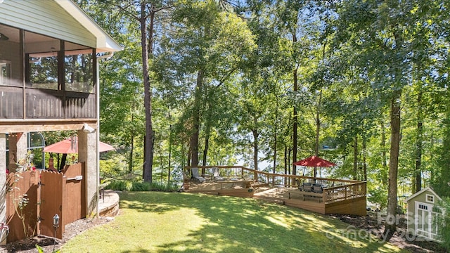 view of yard featuring a wooden deck, a sunroom, and a shed