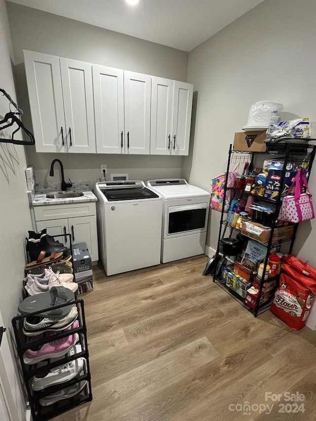 laundry area with sink, independent washer and dryer, light wood-type flooring, and cabinets