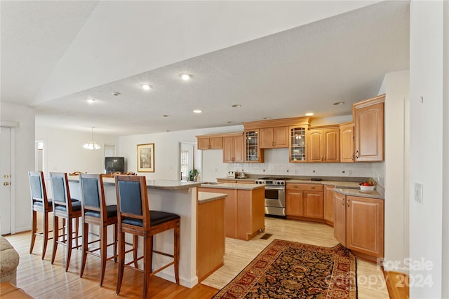 kitchen with a center island, a textured ceiling, a kitchen bar, high end range, and light wood-type flooring