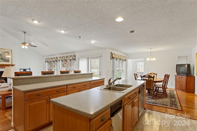 kitchen with stainless steel dishwasher, vaulted ceiling, sink, a center island with sink, and light hardwood / wood-style flooring