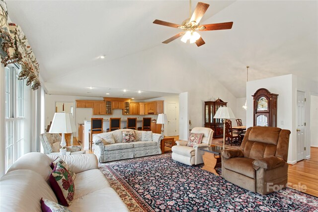 living room featuring ceiling fan, high vaulted ceiling, and light hardwood / wood-style floors