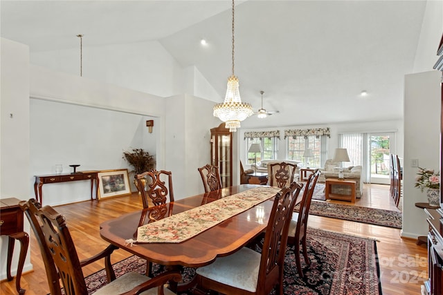 dining room featuring ceiling fan with notable chandelier, light wood-type flooring, and high vaulted ceiling