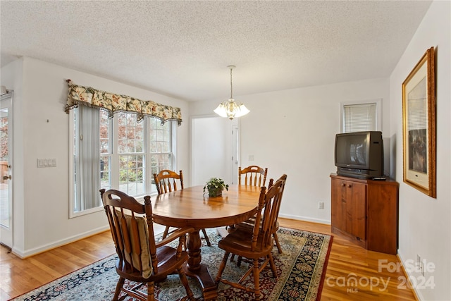 dining room featuring light hardwood / wood-style flooring, a textured ceiling, and a notable chandelier