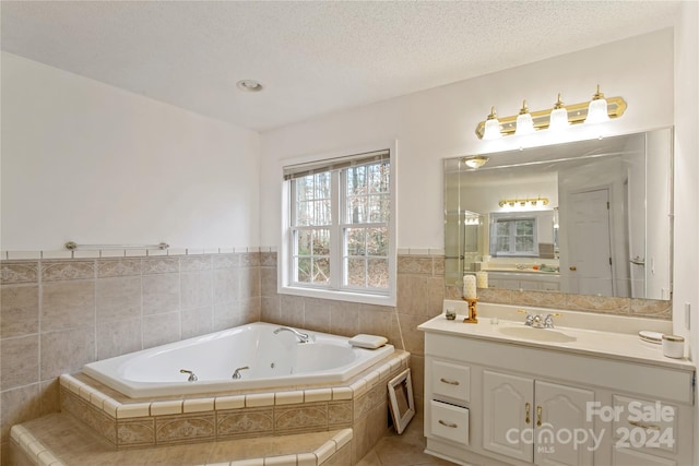 bathroom featuring tile patterned floors, tiled bath, a textured ceiling, vanity, and tile walls