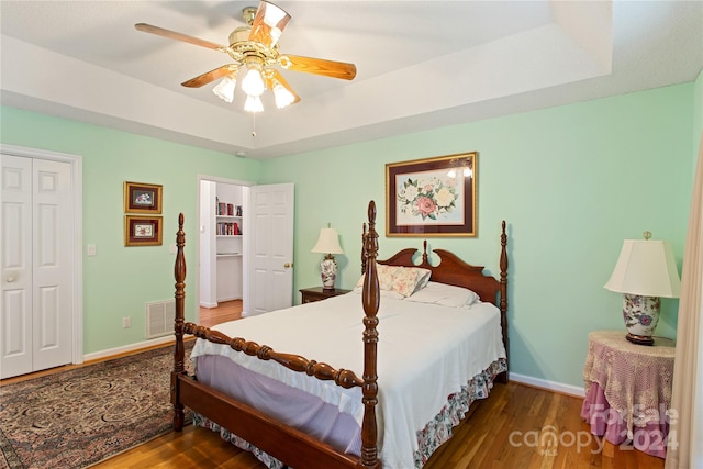 bedroom with a tray ceiling, a closet, ceiling fan, and hardwood / wood-style floors