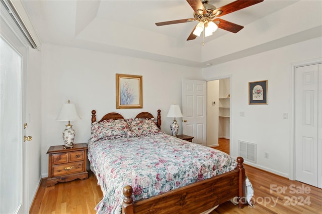 bedroom featuring a tray ceiling, ceiling fan, a closet, and wood-type flooring