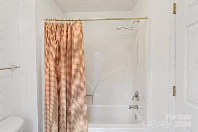 bathroom featuring toilet and shower / tub combo with curtain