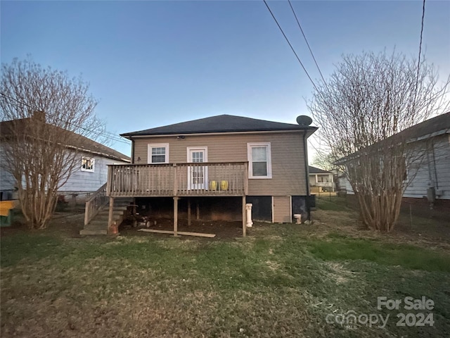 back of property with a wooden deck and a lawn