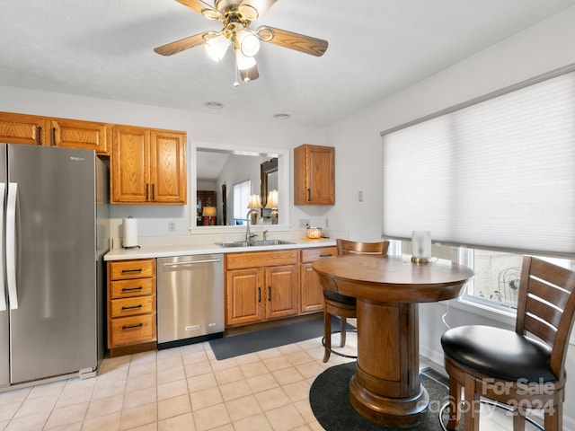 kitchen featuring vaulted ceiling, light tile patterned floors, stainless steel appliances, ceiling fan, and sink