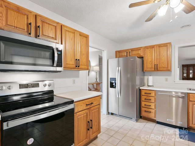 kitchen featuring a textured ceiling, light tile patterned floors, ceiling fan, and stainless steel appliances