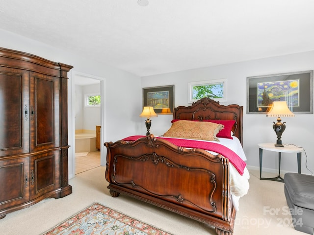 bedroom featuring multiple windows, connected bathroom, and light colored carpet