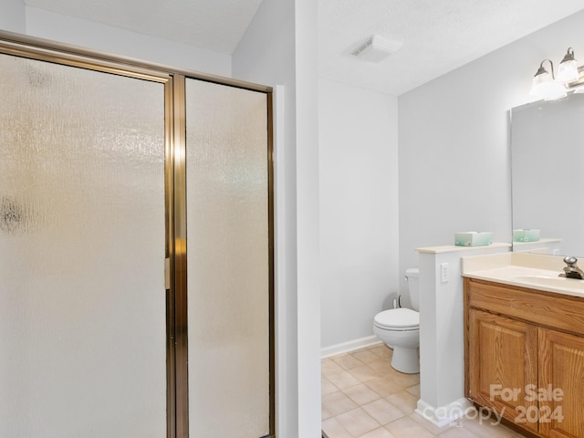 bathroom with vanity, tile patterned flooring, a textured ceiling, a shower with shower door, and toilet