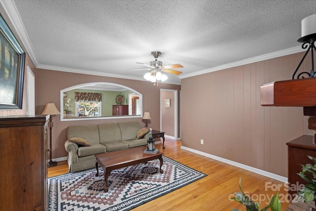 living room featuring a textured ceiling, crown molding, ceiling fan, and hardwood / wood-style flooring