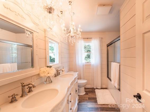 full bathroom featuring enclosed tub / shower combo, vanity, toilet, and a wealth of natural light