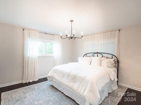 bedroom featuring a chandelier and dark wood-type flooring