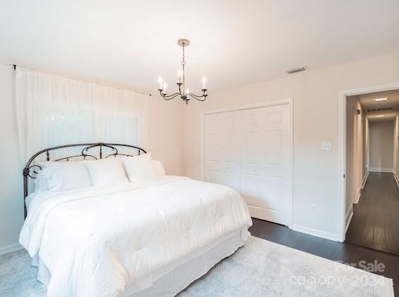 bedroom with an inviting chandelier, a closet, and dark hardwood / wood-style flooring