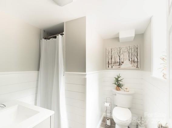 bathroom with a shower with shower curtain, vanity, and toilet