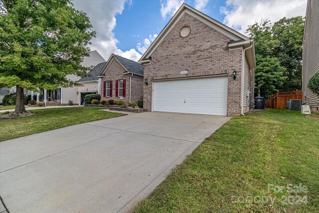 view of property with cooling unit, a garage, and a front lawn