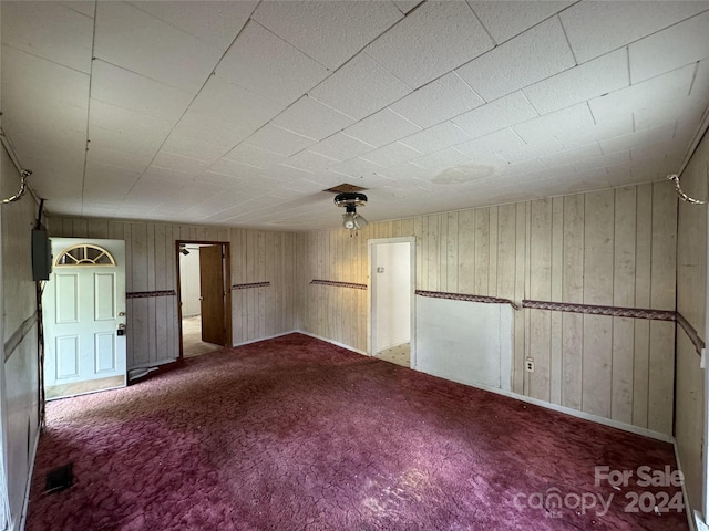 carpeted empty room with wooden walls