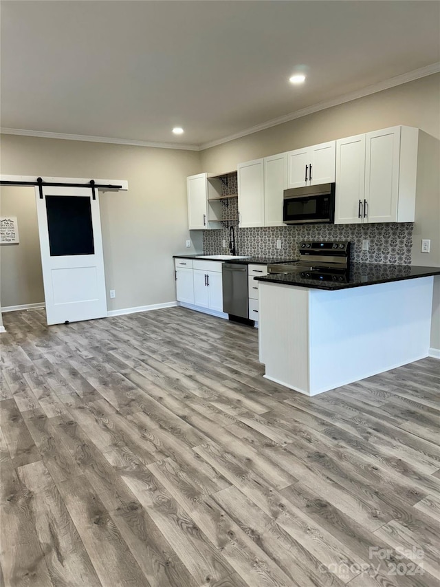 kitchen featuring white cabinets, a barn door, stainless steel appliances, and light hardwood / wood-style flooring