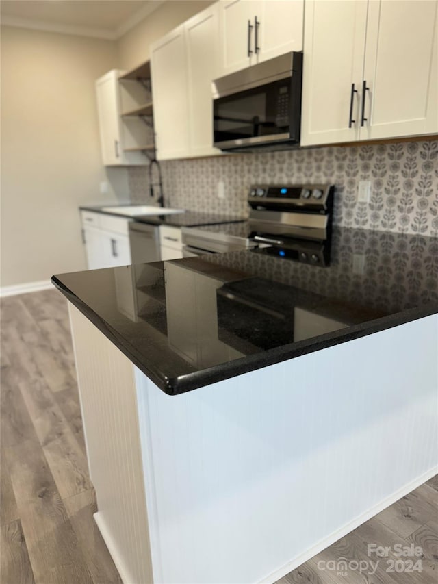 kitchen with tasteful backsplash, white cabinets, dark wood-type flooring, and appliances with stainless steel finishes