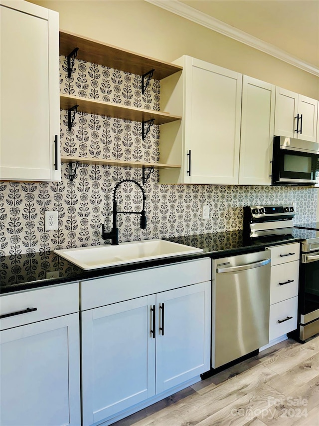 kitchen featuring appliances with stainless steel finishes, white cabinetry, ornamental molding, and sink