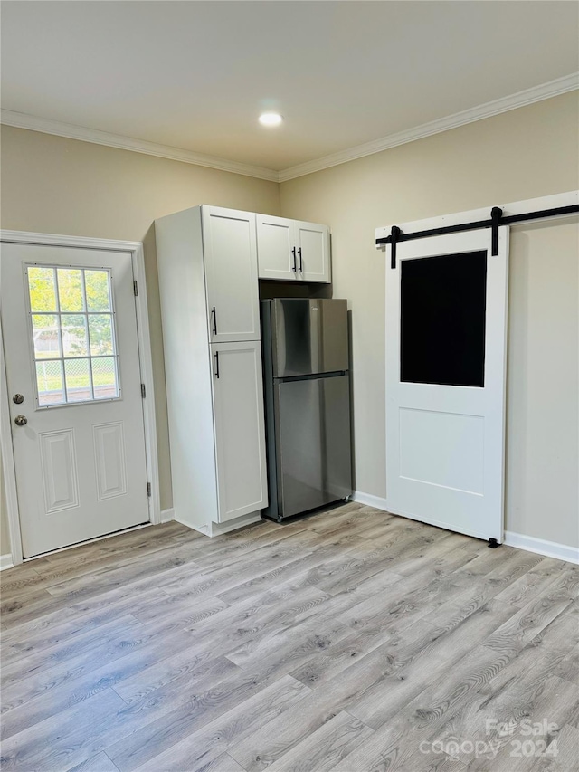 kitchen featuring light hardwood / wood-style floors, a barn door, white cabinetry, and stainless steel refrigerator