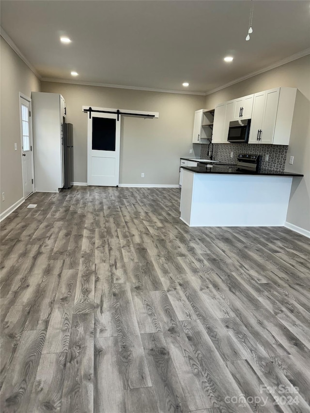 kitchen with white cabinetry, a barn door, kitchen peninsula, light hardwood / wood-style floors, and appliances with stainless steel finishes