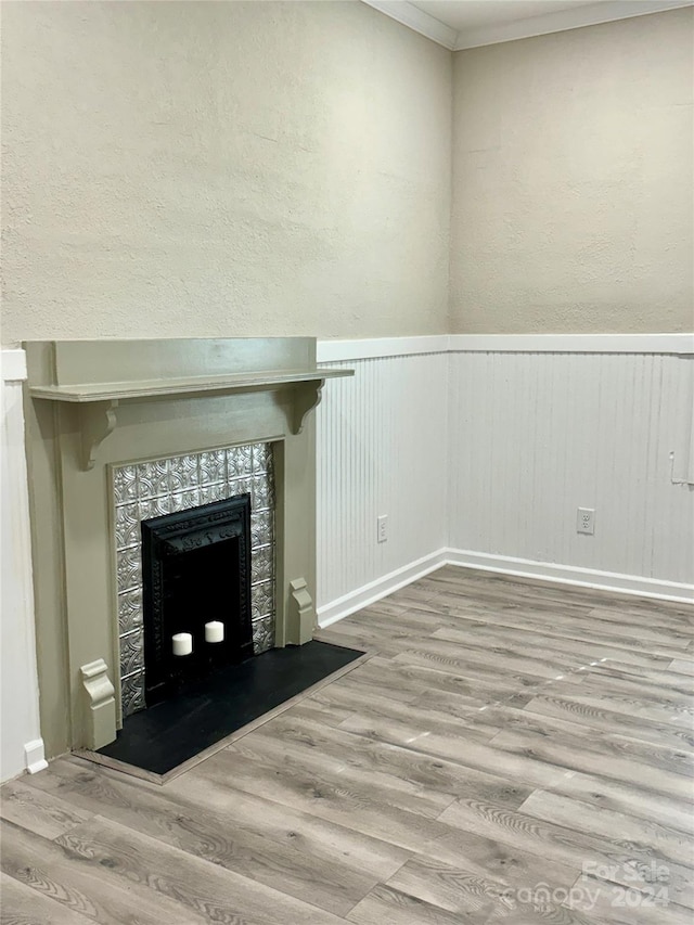 unfurnished living room featuring a tile fireplace, wood-type flooring, and ornamental molding