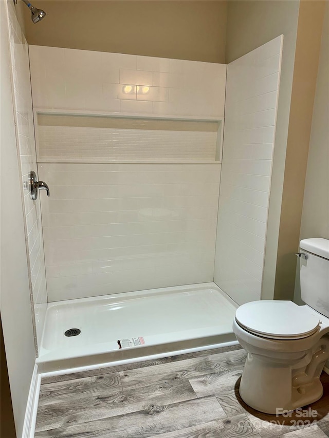 bathroom featuring tiled shower and toilet