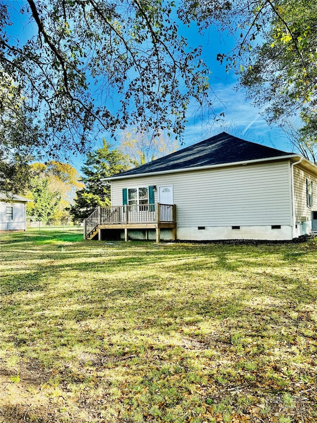 rear view of house featuring a wooden deck and a yard