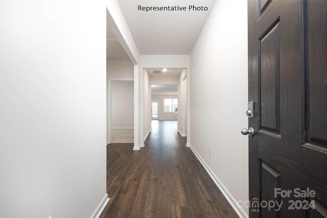 hallway featuring visible vents, dark wood-style floors, and baseboards