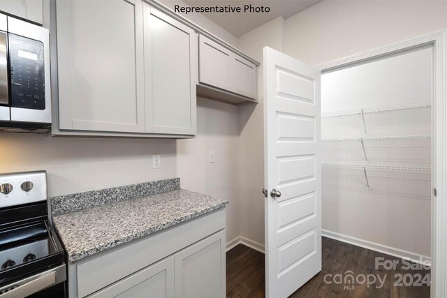 kitchen featuring light stone counters, stainless steel appliances, and dark hardwood / wood-style floors