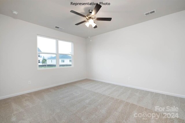 carpeted spare room featuring ceiling fan