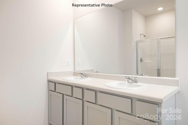 bathroom featuring a shower with door and vanity