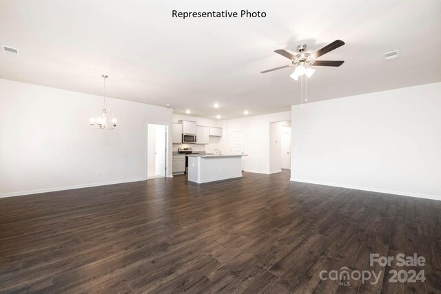 unfurnished living room featuring dark wood-type flooring, ceiling fan with notable chandelier, and sink