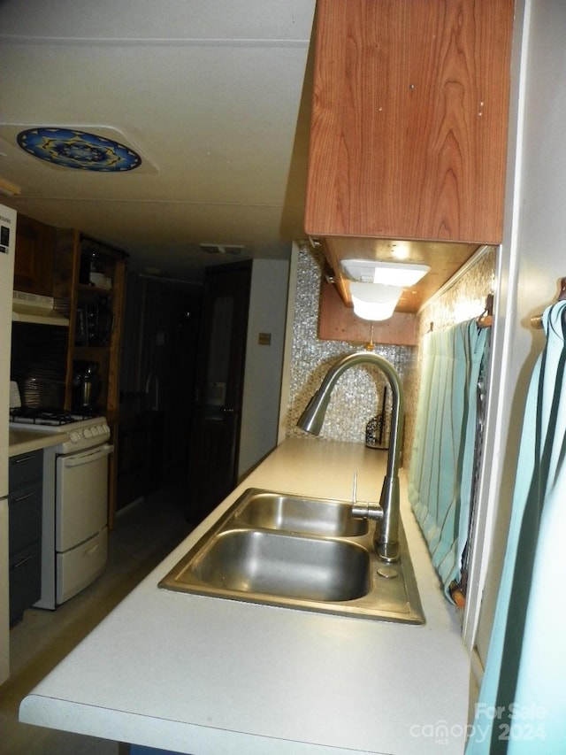 kitchen featuring tasteful backsplash, white range with gas stovetop, and sink