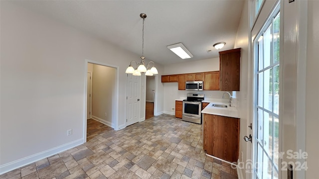 kitchen featuring a notable chandelier, sink, stainless steel appliances, and hanging light fixtures