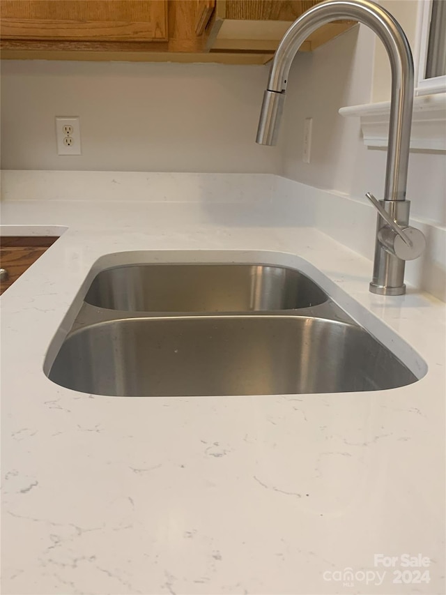 room details featuring light stone countertops and sink