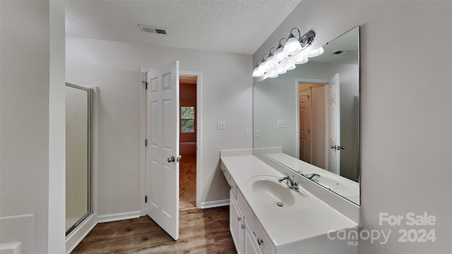 bathroom featuring hardwood / wood-style flooring, vanity, an enclosed shower, and a textured ceiling