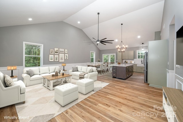 living area featuring high vaulted ceiling, recessed lighting, wainscoting, and light wood-style floors