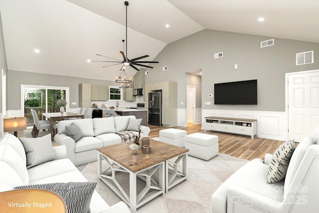 living room featuring light wood-type flooring, wainscoting, and visible vents