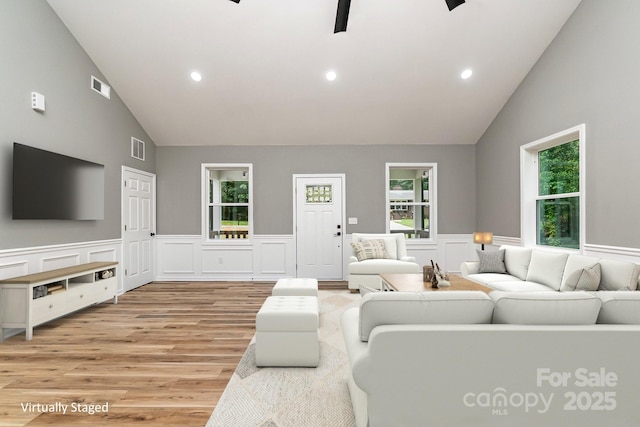 living room with a wainscoted wall, recessed lighting, visible vents, and light wood-style floors