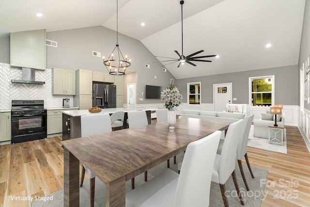 dining room with high vaulted ceiling, wainscoting, visible vents, and light wood finished floors