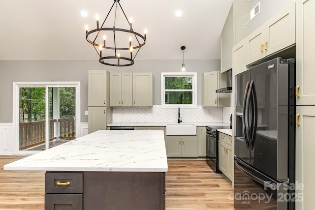 kitchen with a kitchen island, a sink, visible vents, wainscoting, and black appliances