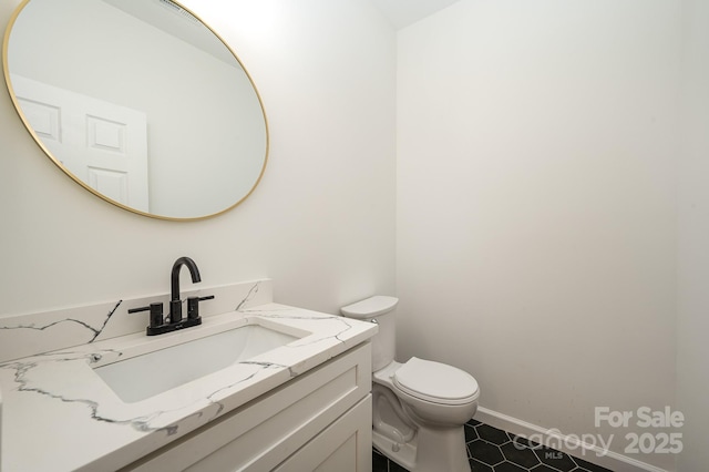 bathroom with vanity, toilet, and baseboards