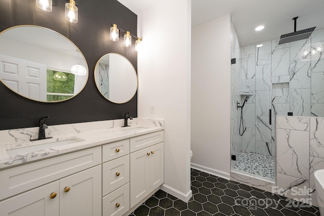 full bathroom with double vanity, a marble finish shower, baseboards, and a sink