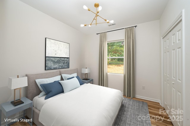 bedroom featuring a closet, visible vents, a notable chandelier, and wood finished floors